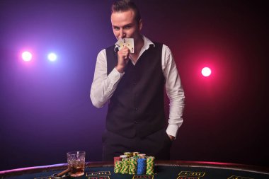 Zengin adam siyah arka plan üzerinde bir casino bir heyecan ile poker oynuyor.