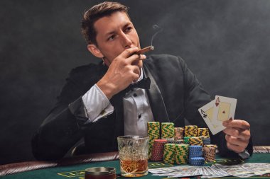 Yakışıklı duygusal adam kumarhanede beyaz spot ışıklarına karşı poker oynuyor..