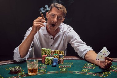 Yakışıklı duygusal adam kumarhanede beyaz spot ışıklarına karşı poker oynuyor..