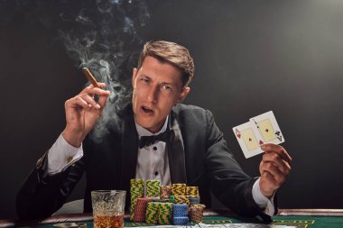 Yakışıklı duygusal adam kumarhanede beyaz spot ışıklarına karşı poker oynuyor..