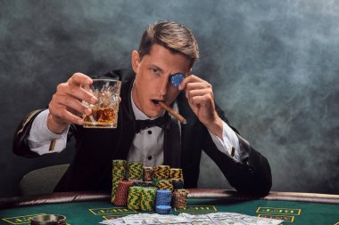 Yakışıklı duygusal adam kumarhanede beyaz spot ışıklarına karşı poker oynuyor..