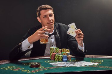 Yakışıklı duygusal adam kumarhanede beyaz spot ışıklarına karşı poker oynuyor..