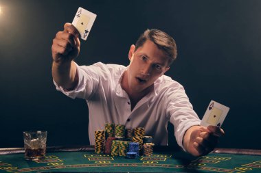 Yakışıklı duygusal adam kumarhanede beyaz spot ışıklarına karşı poker oynuyor..