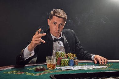 Yakışıklı duygusal adam kumarhanede beyaz spot ışıklarına karşı poker oynuyor..