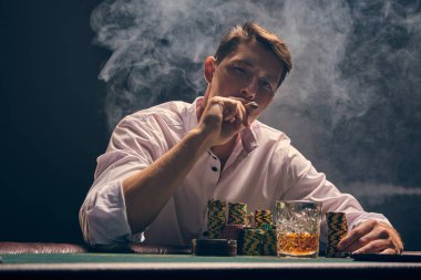 Yakışıklı duygusal adam kumarhanede beyaz spot ışıklarına karşı poker oynuyor..
