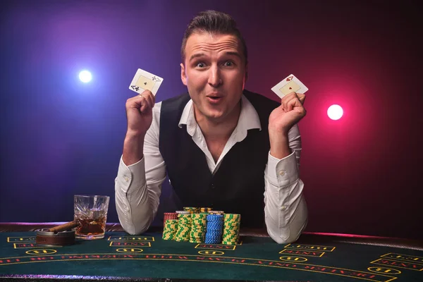 Hombre rico está jugando al póquer con una emoción en un casino en el fondo negro . — Foto de Stock