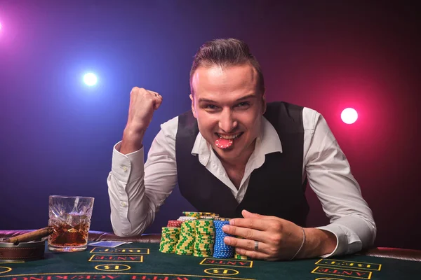 Hombre rico está jugando al póquer con una emoción en un casino en el fondo negro . —  Fotos de Stock