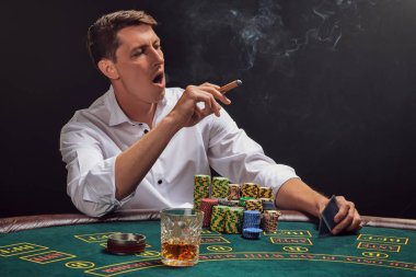 Yakışıklı duygusal adam kumarhanede beyaz spot ışıklarına karşı poker oynuyor..