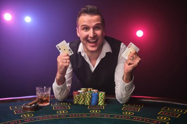 Zengin adam siyah arka plan üzerinde bir casino bir heyecan ile poker oynuyor.