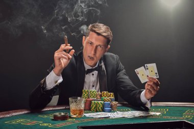 Yakışıklı duygusal adam kumarhanede beyaz spot ışıklarına karşı poker oynuyor..