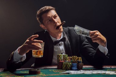 Yakışıklı duygusal adam kumarhanede beyaz spot ışıklarına karşı poker oynuyor..