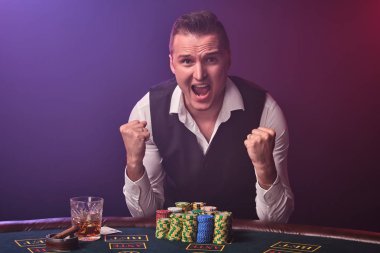 Zengin adam siyah arka plan üzerinde bir casino bir heyecan ile poker oynuyor.