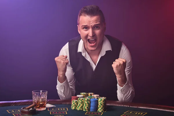 Reicher Mann pokert mit Aufregung in einem Casino auf schwarzem Hintergrund. — Stockfoto