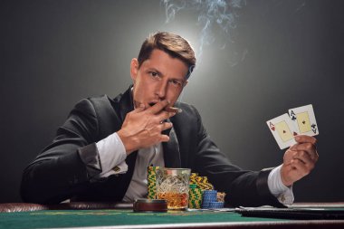 Yakışıklı duygusal adam kumarhanede beyaz spot ışıklarına karşı poker oynuyor..