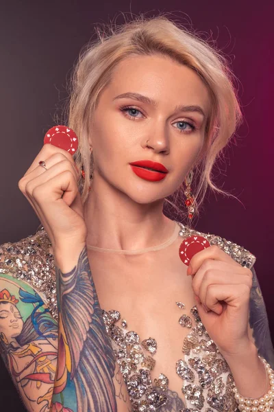 아름다운 헤어 스타일과 완벽한 메이크업을 가진 금발의 여자는 그녀의 손에 빨간 도박 칩포즈입니다. 카지노, 포커. — 스톡 사진