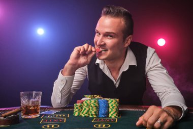 Zengin adam siyah arka plan üzerinde bir casino bir heyecan ile poker oynuyor.