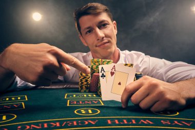 Yakışıklı duygusal adam kumarhanede beyaz spot ışıklarına karşı poker oynuyor..