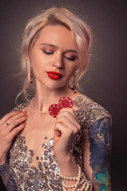 Güzel bir saç modeli ve mükemmel makyaj ile Sarışın kadın elinde kırmızı kumar cips ile poz veriyor. Casino, poker.