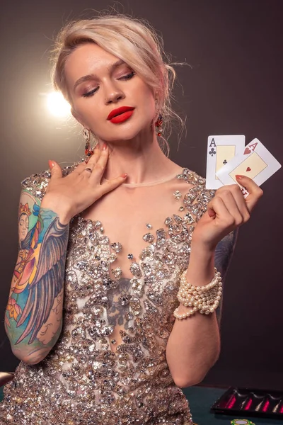 Szőke nő, gyönyörű frizura és tökéletes make-up pózol kártyákkal a kezében. Kaszinó, póker. — Stock Fotó