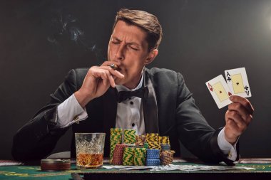 Yakışıklı duygusal adam kumarhanede beyaz spot ışıklarına karşı poker oynuyor..