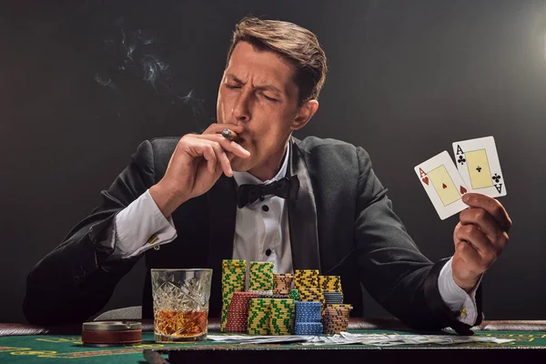 漂亮的情绪化的男人正坐在赌场的桌旁，面对着一个白人聚光灯打扑克. — 图库照片