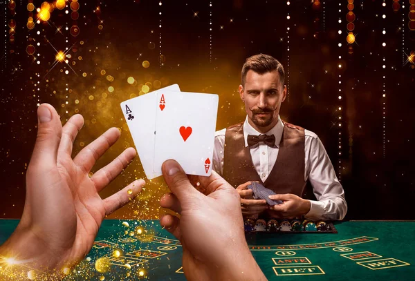 Portrait of a croupier is holding playing cards, gambling chips on table. Black background — Stock Photo, Image