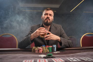 Yakışıklı sakallı adam kumarhanede masada poker oynuyor..