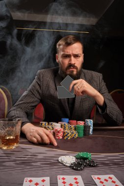 Yakışıklı sakallı adam kumarhanede masada poker oynuyor..
