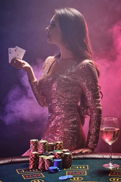Brunette girl with a perfect hairstyle and bright make-up is posing with playing cards in her hands. Casino, poker.