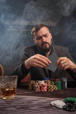 Yakışıklı sakallı adam kumarhanede masada poker oynuyor..