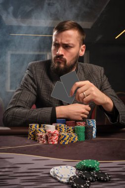 Yakışıklı sakallı adam kumarhanede masada poker oynuyor..