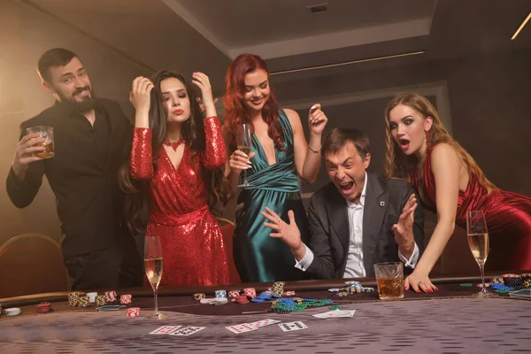 Grupo de jóvenes amigos ricos están jugando al póquer en un casino . — Foto de Stock