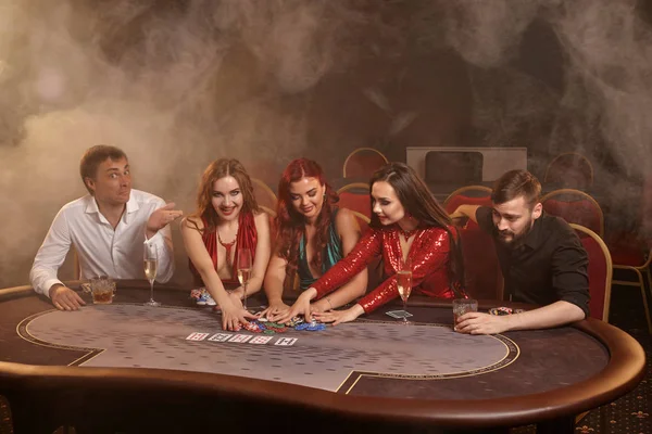 Skupina mladých bohatých přátel hrají poker v kasinu. — Stock fotografie