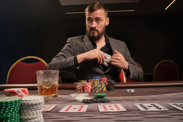 Snygg skäggig man spelar poker sitter vid bordet i kasino. — Stockfoto