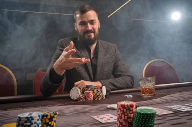 Yakışıklı sakallı adam kumarhanede masada poker oynuyor..