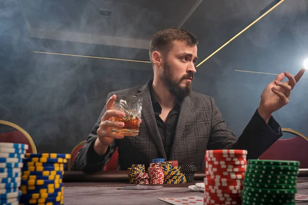 Hombre barbudo guapo está jugando póquer sentado en la mesa en el casino . — Foto de Stock