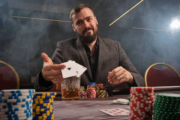 Yakışıklı sakallı adam kumarhanede masada poker oynuyor..
