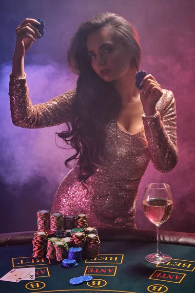 Chica morena con un peinado perfecto y maquillaje brillante está posando con fichas de juego en sus manos. Casino, poker . — Foto de Stock