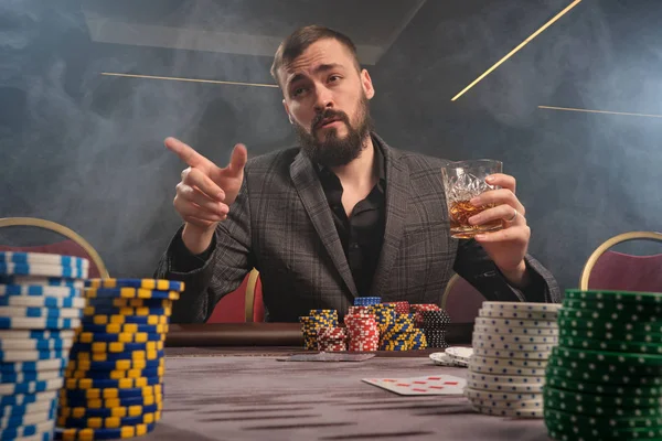 Hombre barbudo guapo está jugando póquer sentado en la mesa en el casino . —  Fotos de Stock