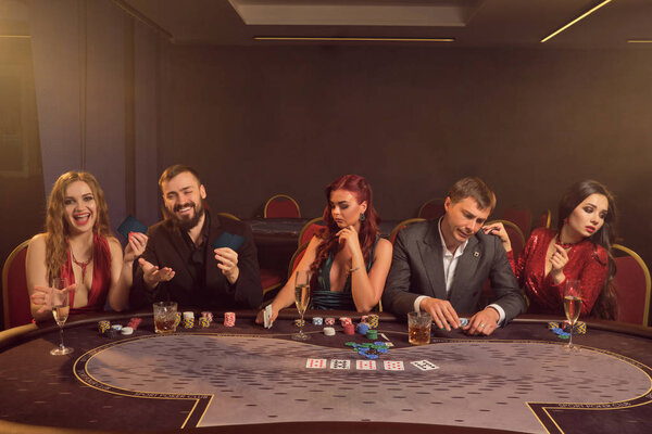 Group of a young wealthy friends are playing poker at a casino.