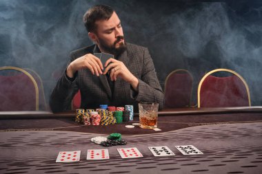 Yakışıklı sakallı adam kumarhanede masada poker oynuyor..