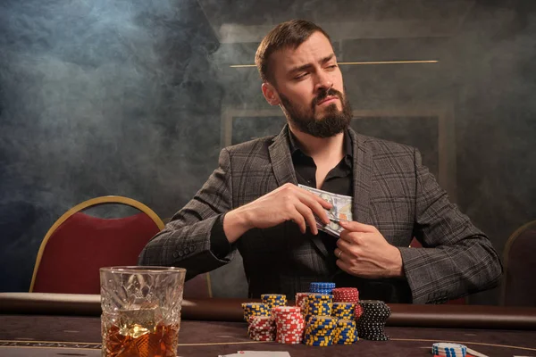 Przystojny brodaty mężczyzna gra w pokera siedzi przy stole w kasynie. — Zdjęcie stockowe