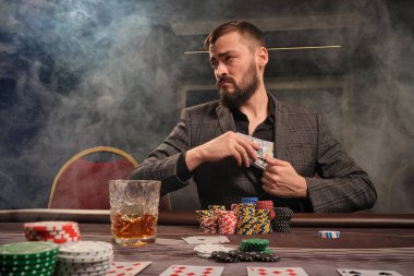 Yakışıklı sakallı adam kumarhanede masada poker oynuyor..