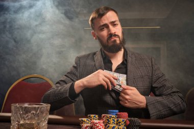 Yakışıklı sakallı adam kumarhanede masada poker oynuyor..