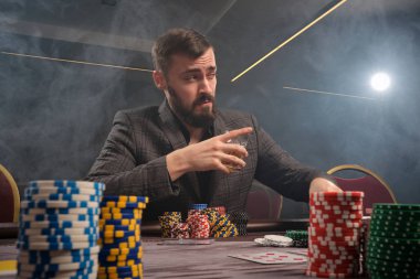 Yakışıklı sakallı adam kumarhanede masada poker oynuyor..