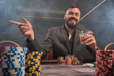 Yakışıklı sakallı adam kumarhanede masada poker oynuyor..