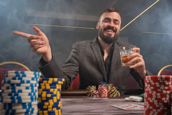 Hombre barbudo guapo está jugando póquer sentado en la mesa en el casino . —  Fotos de Stock