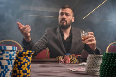 Yakışıklı sakallı adam kumarhanede masada poker oynuyor..