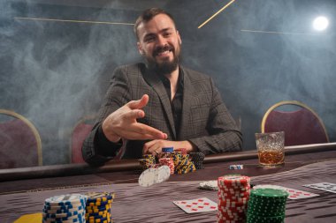 Yakışıklı sakallı adam kumarhanede masada poker oynuyor..