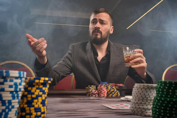 Hombre barbudo guapo está jugando póquer sentado en la mesa en el casino . —  Fotos de Stock